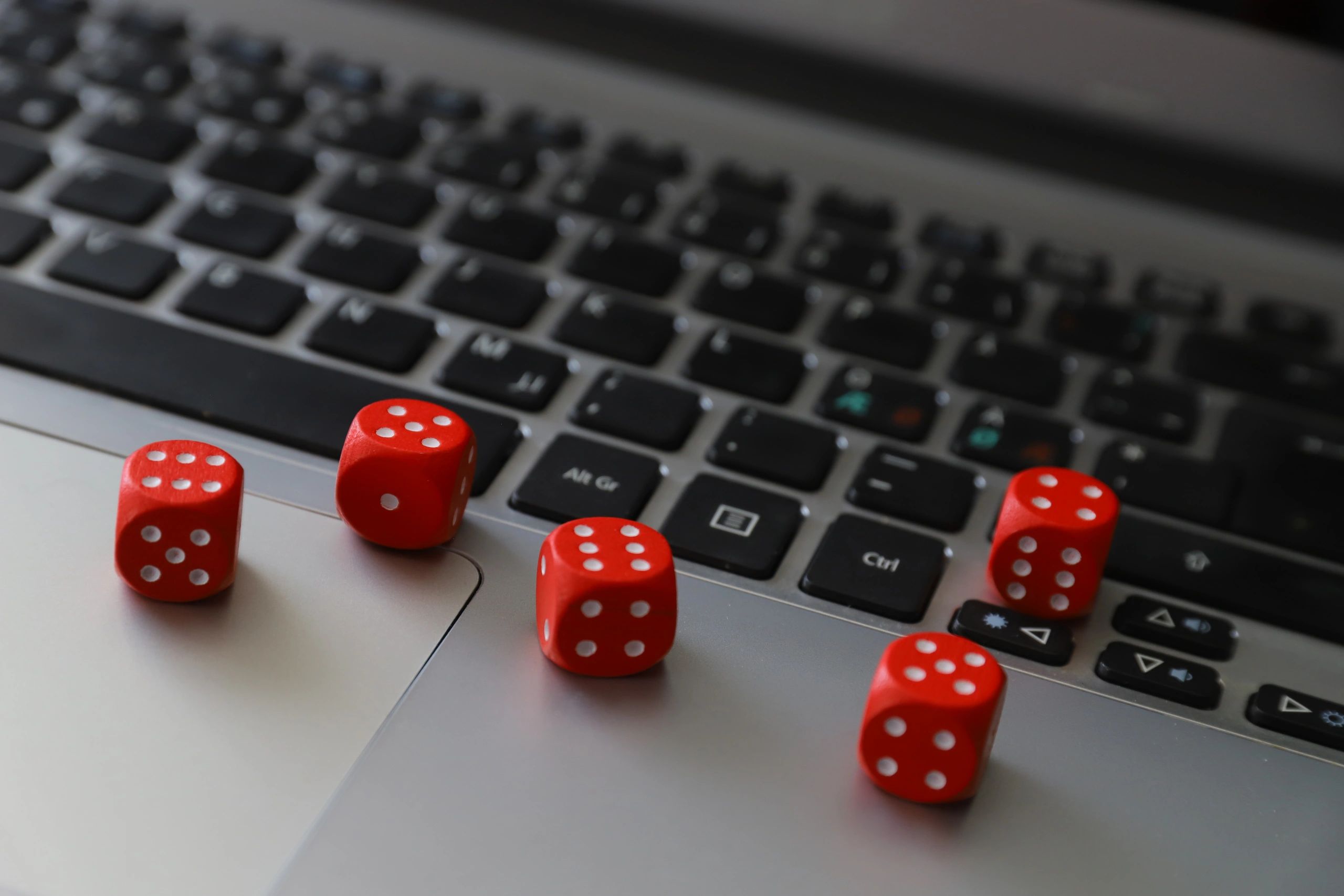 Five red dice spread across a laptop keyboard